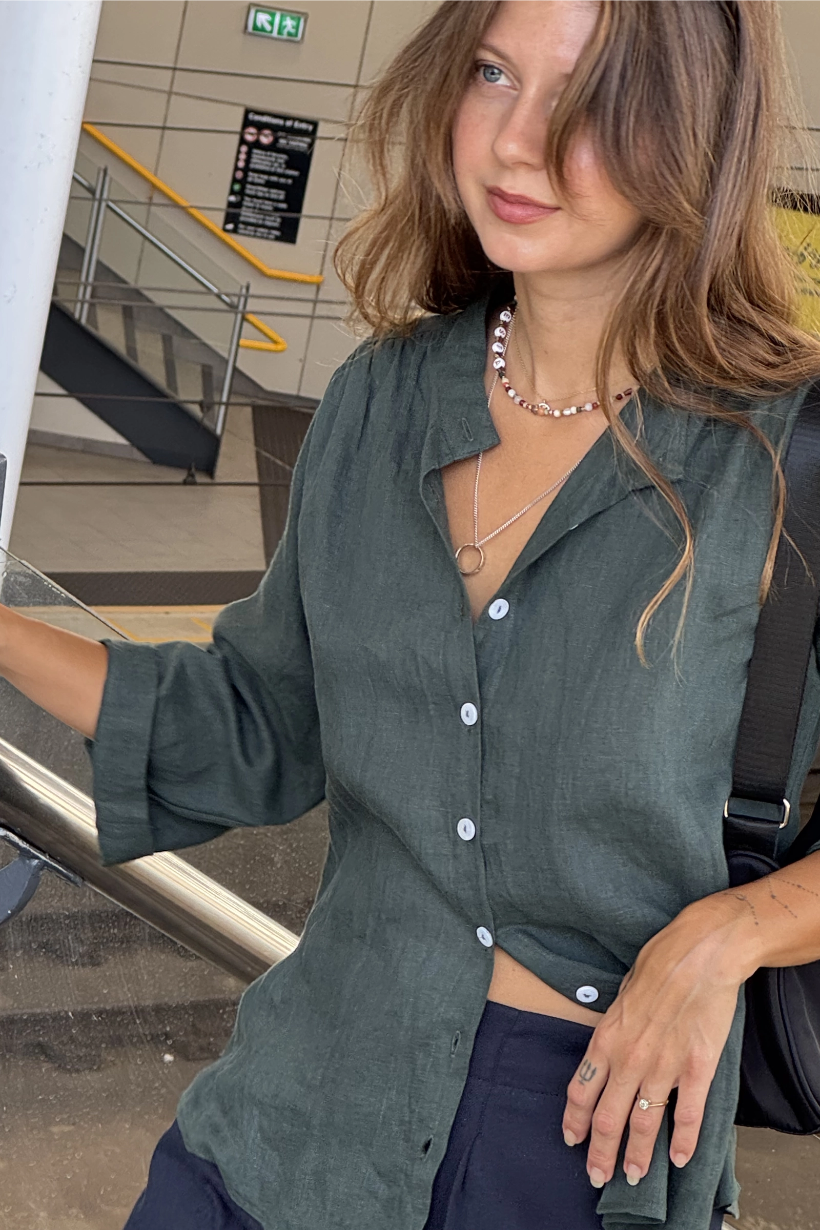 Woman in a green shirt standing on the stairs at a railway station.