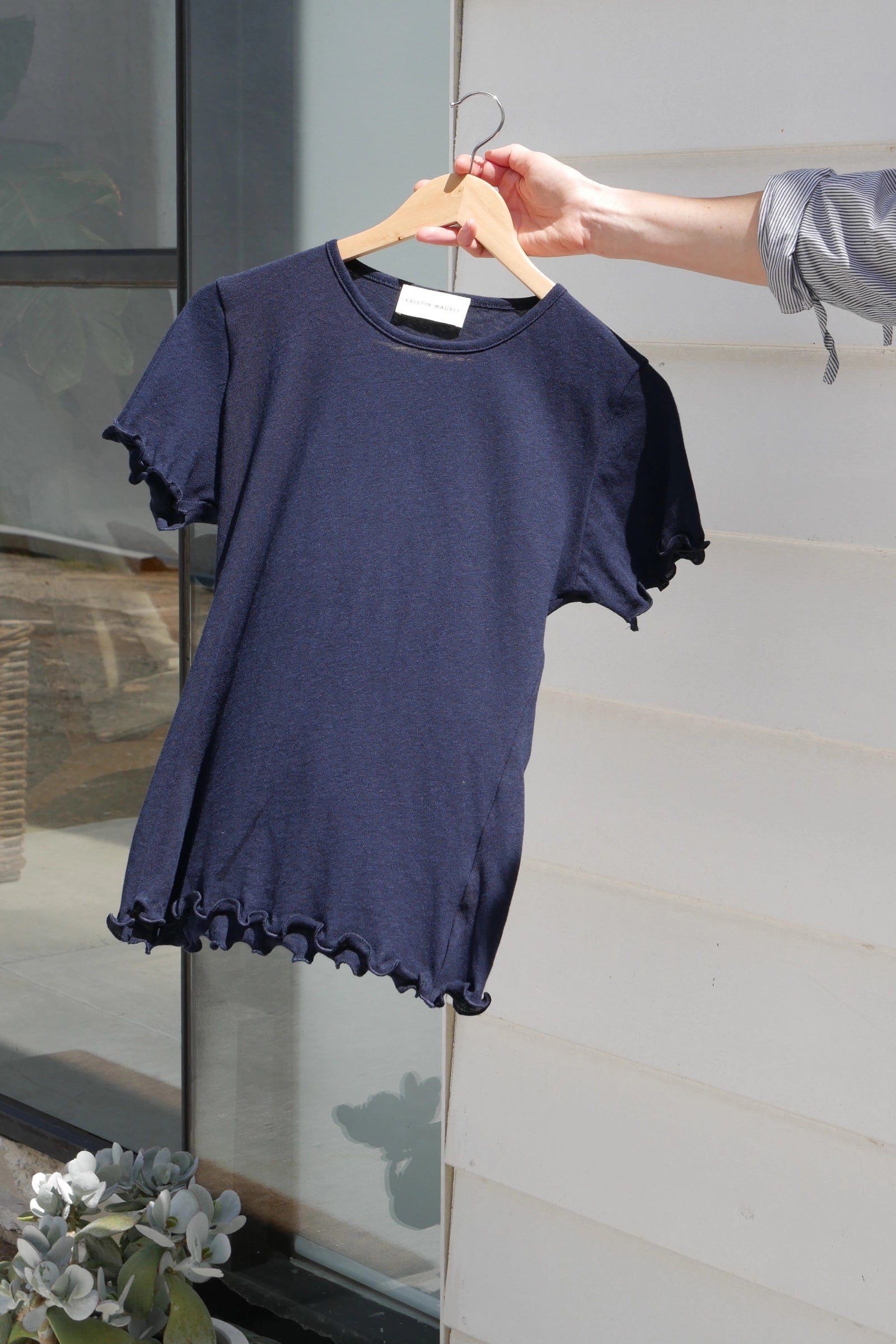 Navy blue t-shirt on a hanger against a neutral background