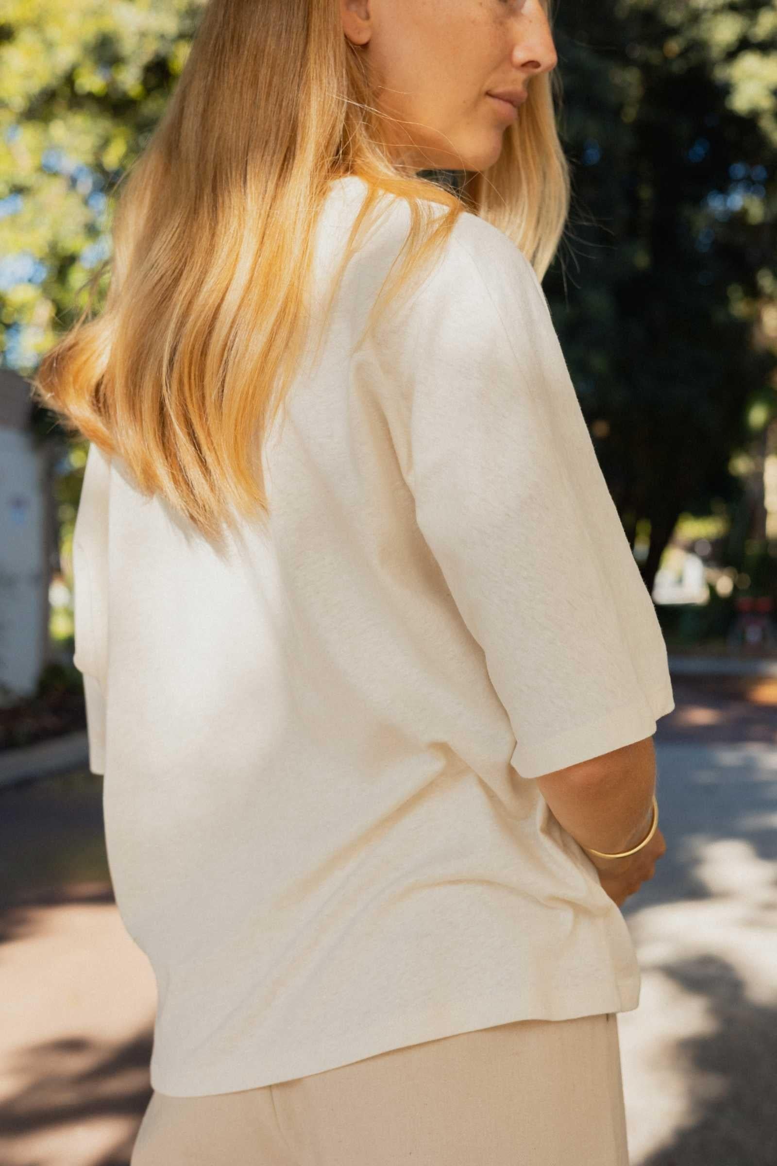 Woman wearing a light-colored Tshirt with a blurred outdoor background