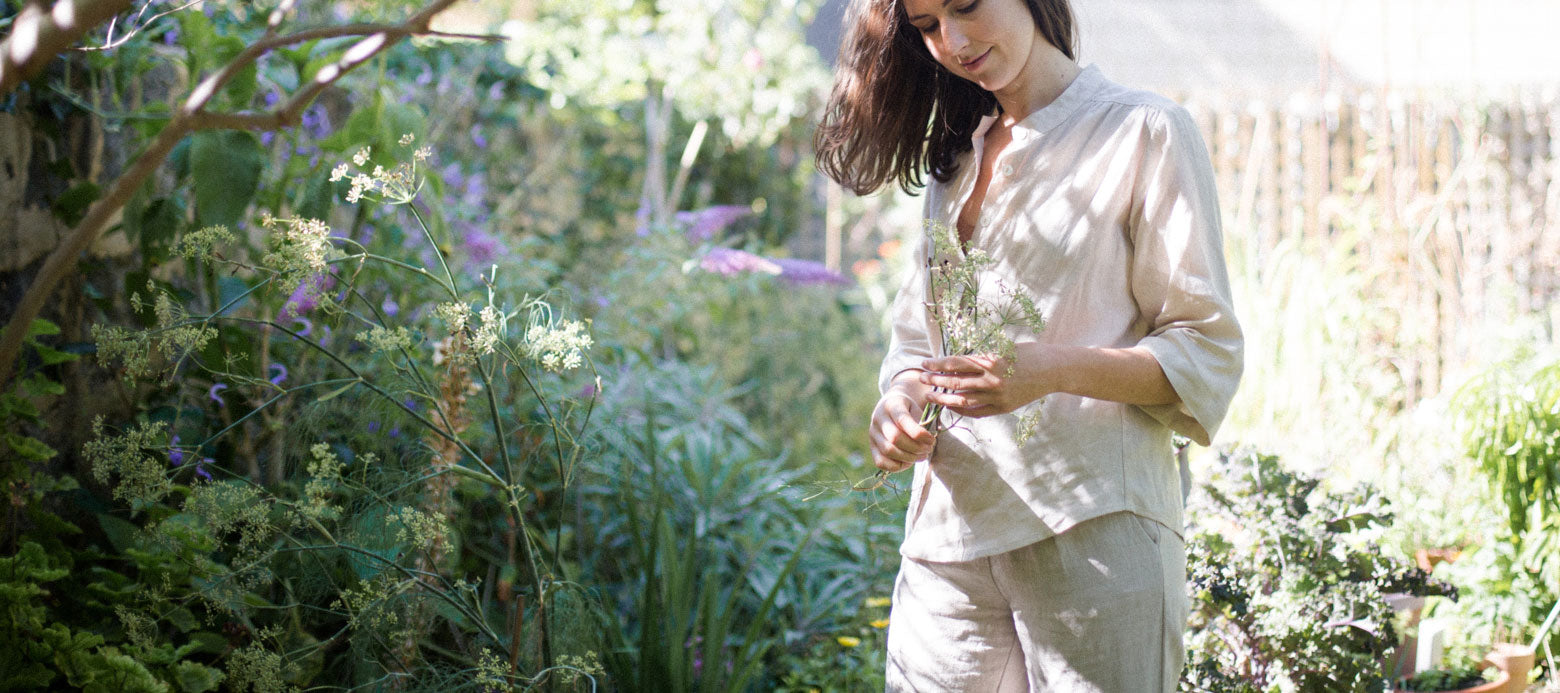 Gardener Casey Lister wearing KRistin Magrit linen blouse and trouser, holding a flower