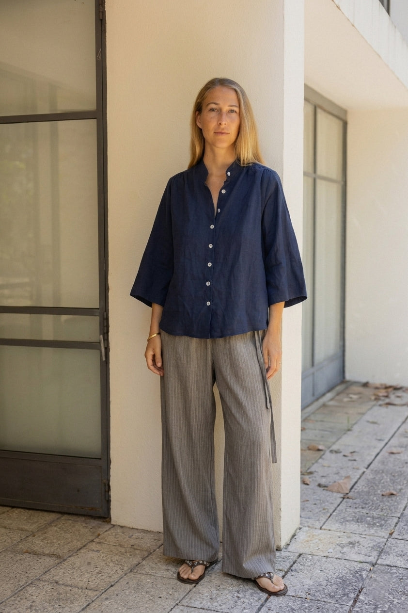Woman wears navy linen blouse grey stripe wool trouser 