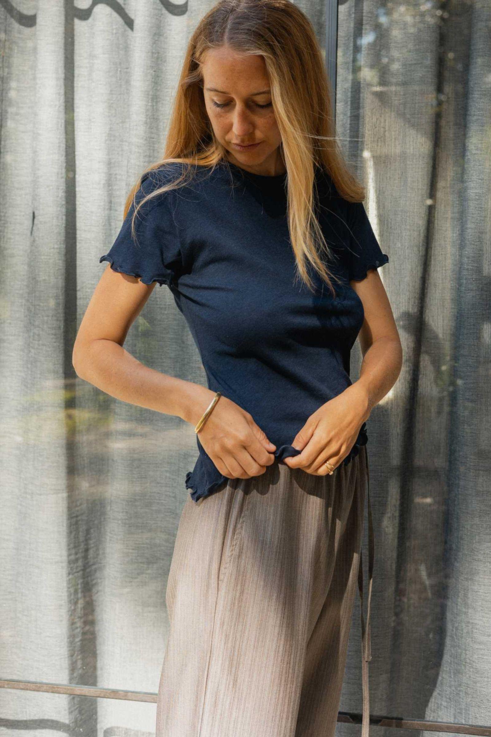 Woman wearing a navy tee showing frill edge hem detail 