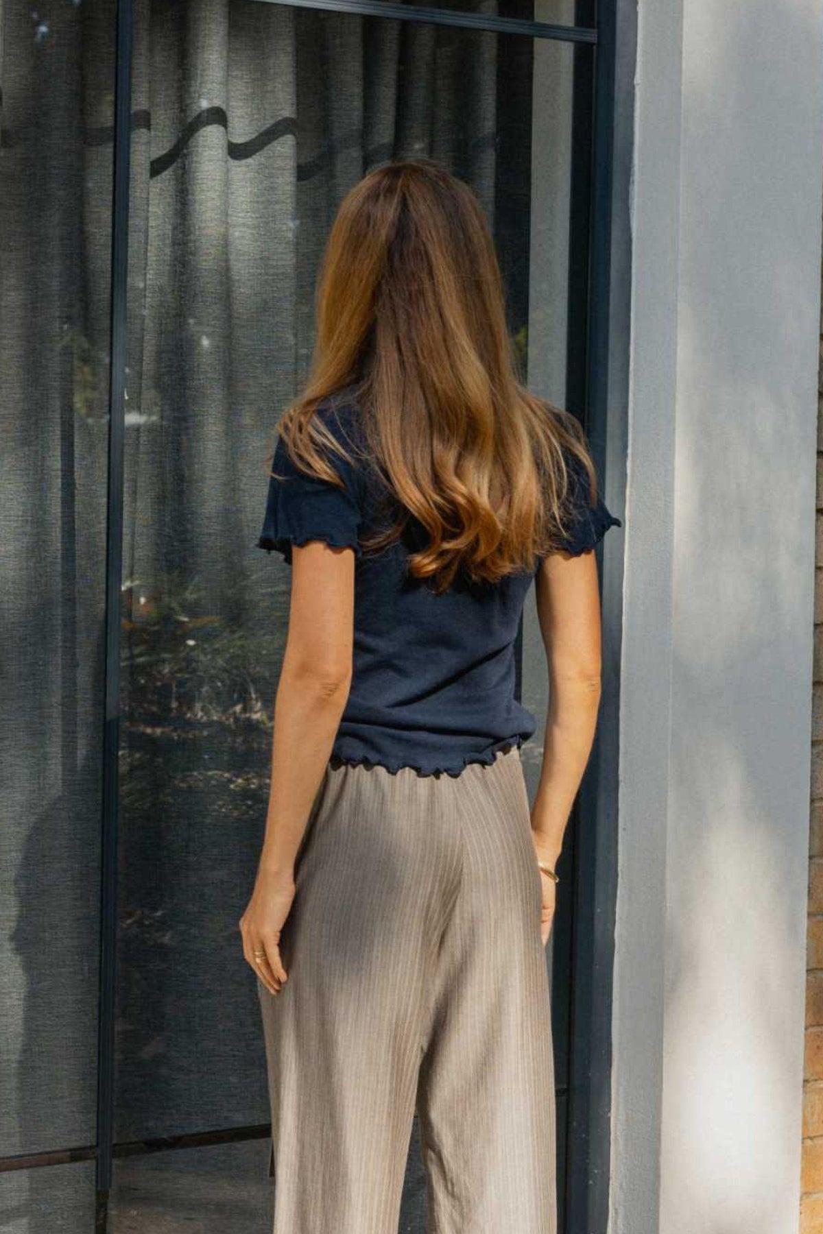 Back View of woman standing in front of a glass door with a blurred background