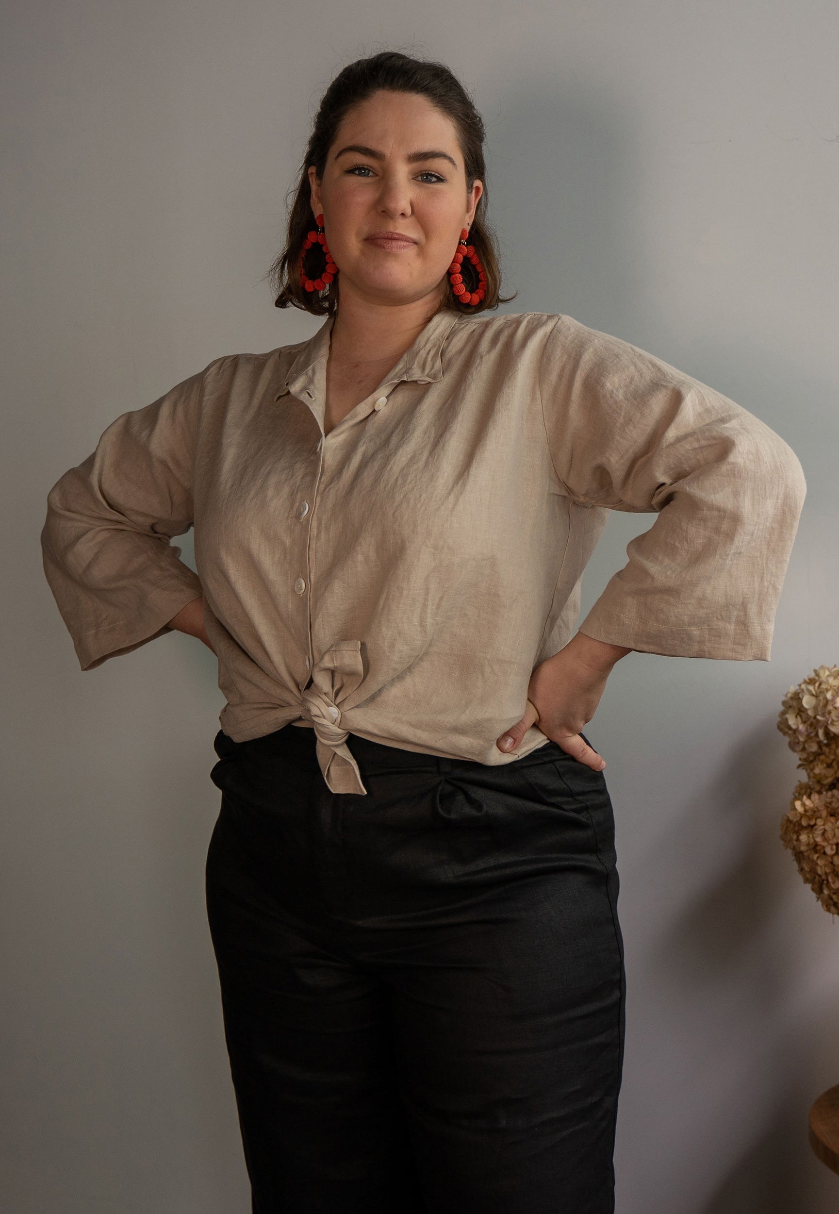 Young woman wears sand linen blouse knotted at the waist