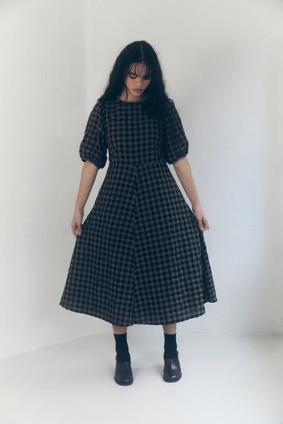 model standing head down front view in a line gingham dress colour mocha and black